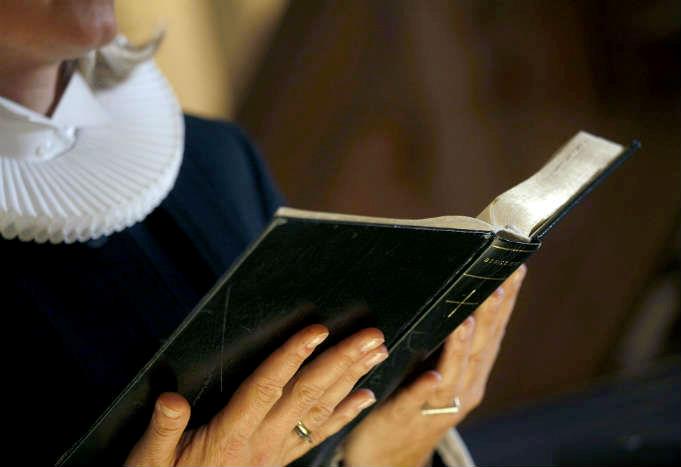 Kvindelig præst læser op af bibelen