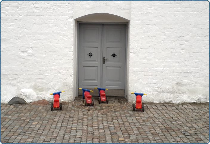 Fire børnescootere parkeret foran kirkedøren